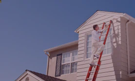 worker painting house exterior
